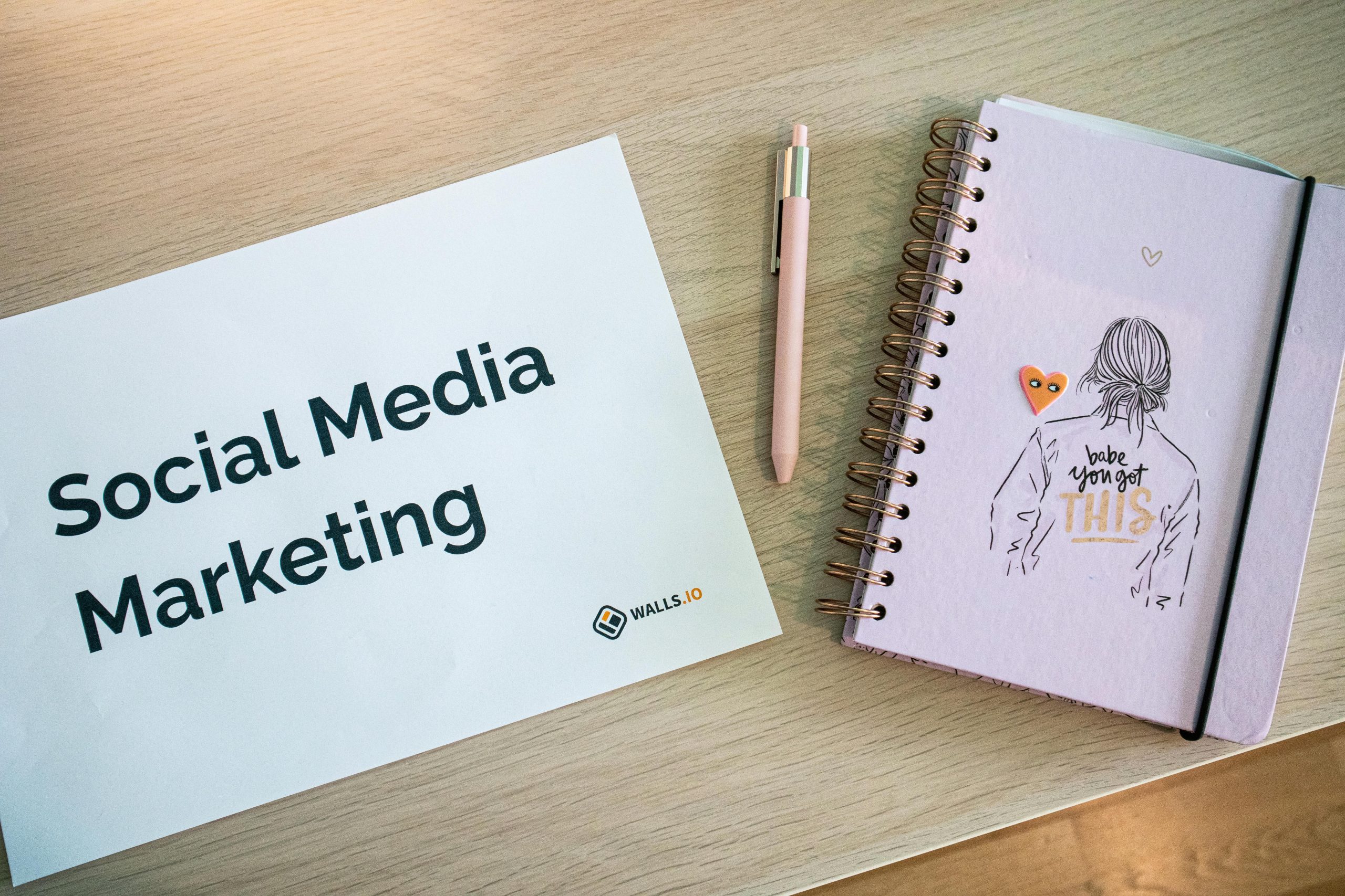 Flat lay of social media marketing paper and motivational notebook on wooden desk.
